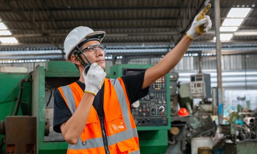 asian man engineering holding walkie-talkie technician inspector manufacturing industry workplace. heavy industrial factory concept.